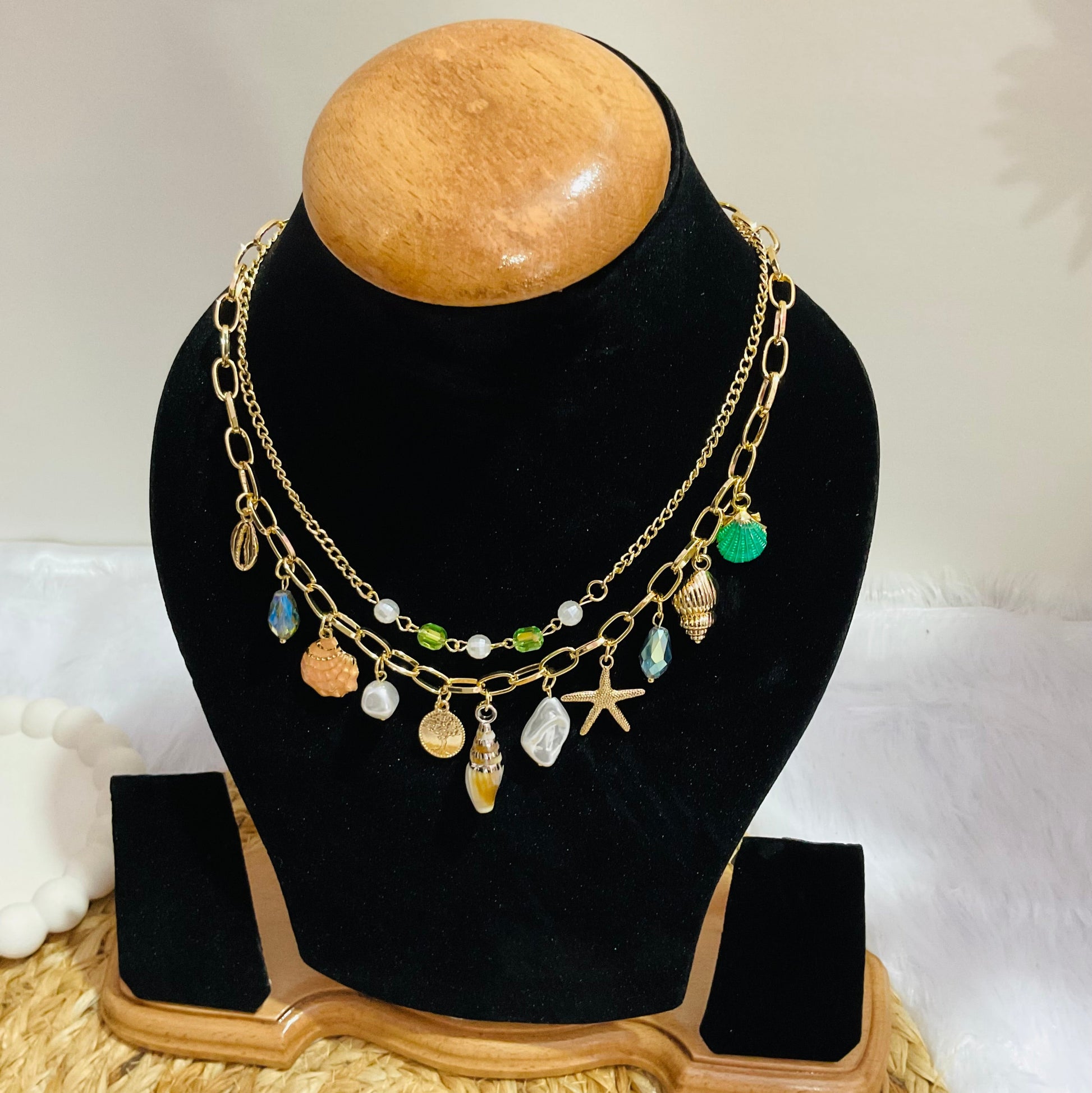 Necklace with various charms on a black bust against a white background