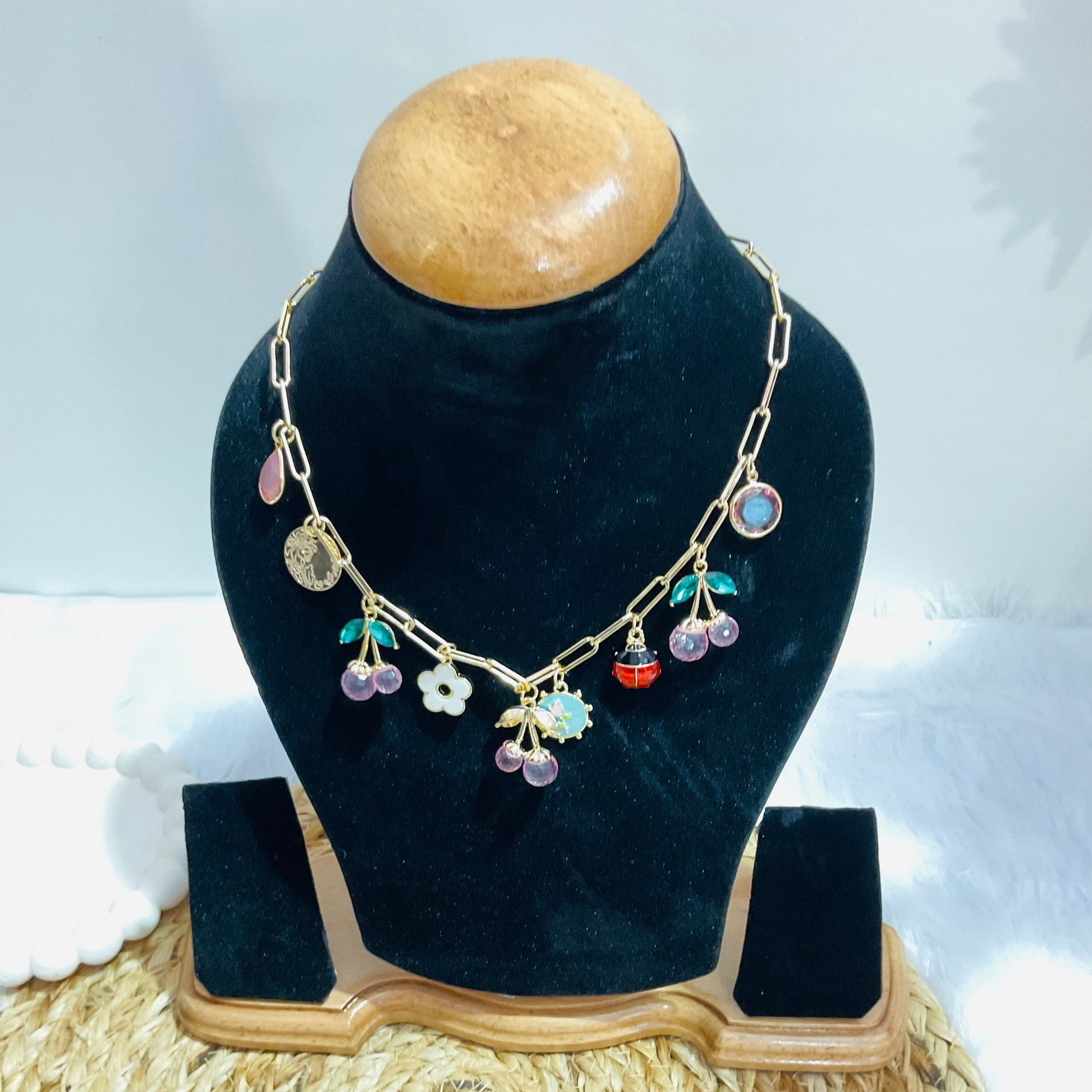 Necklace with colorful charms on a black velvet stand with a white background