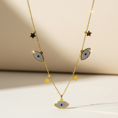Gold necklace with eye-shaped pendants and star accents on a beige background
