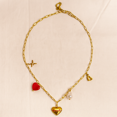 Gold chain necklace with heart-shaped pendants on a beige background