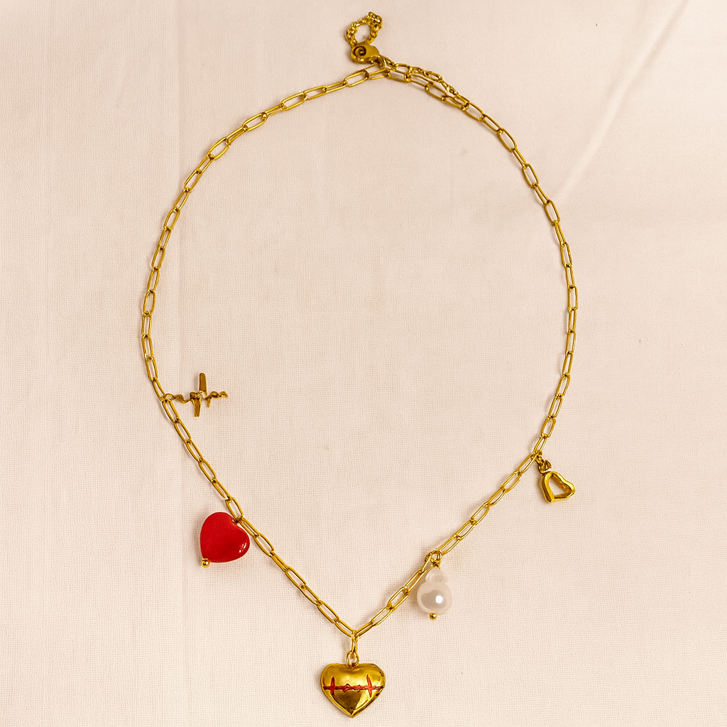 Gold chain necklace with heart-shaped pendants on a beige background