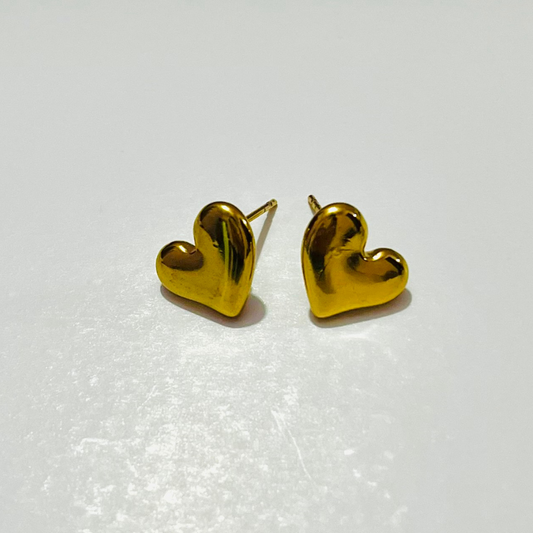 Gold heart-shaped earrings on a light gray background