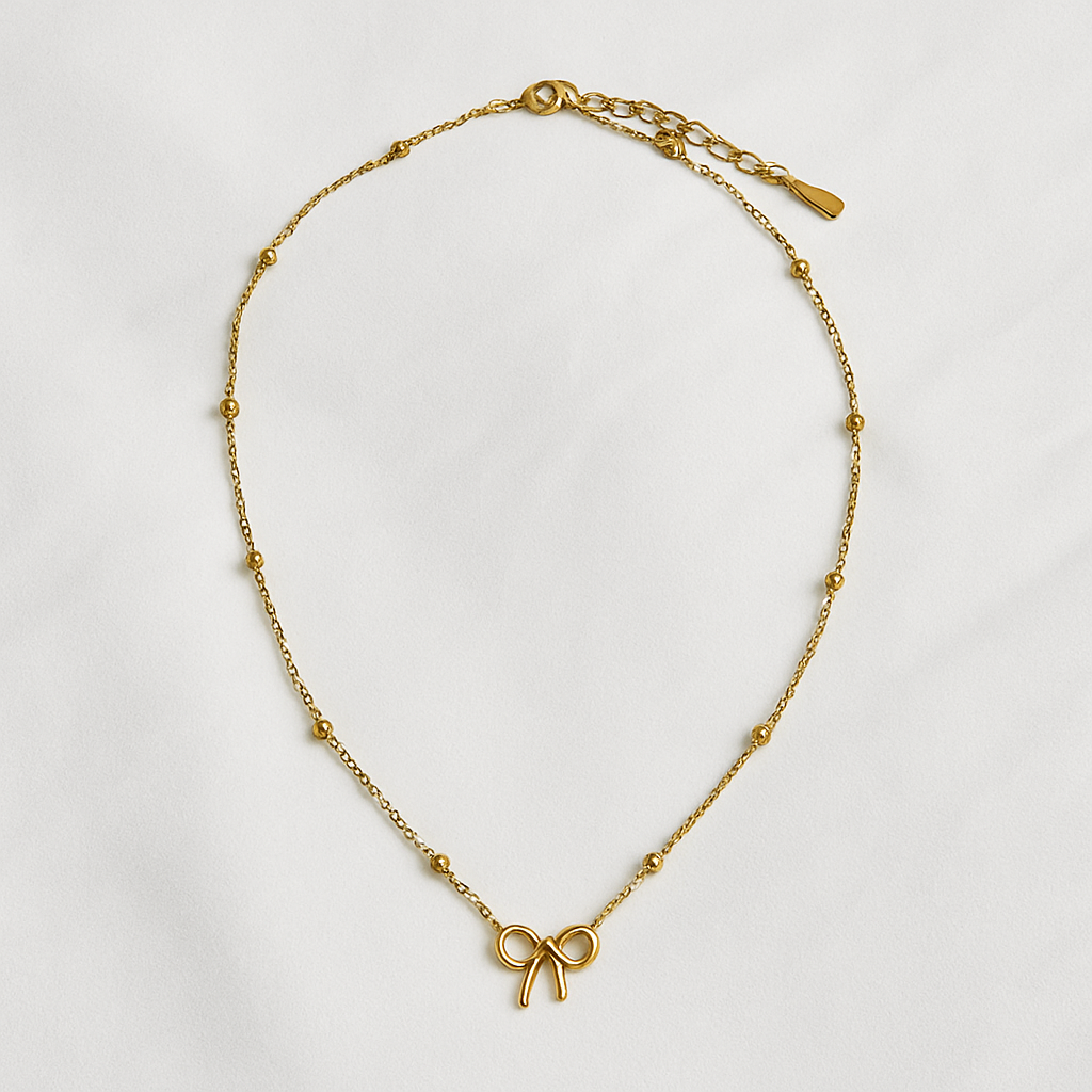 Gold necklace with a bow charm on a light gray background