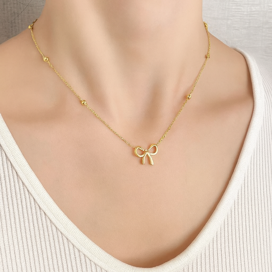Gold necklace with a bow pendant on a mannequin