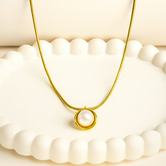 Gold necklace with a pearl pendant on a white background