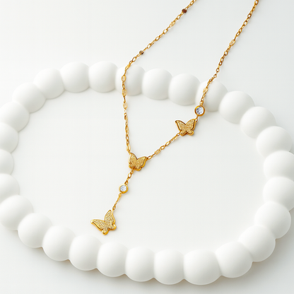 Gold butterfly necklace on a white stone surface
