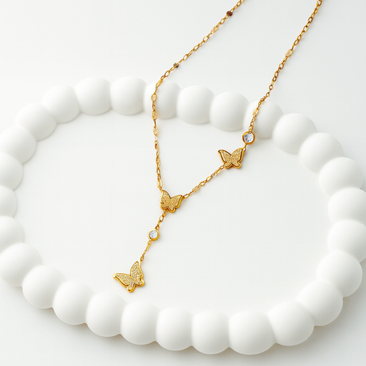 Gold butterfly necklace on a white stone surface