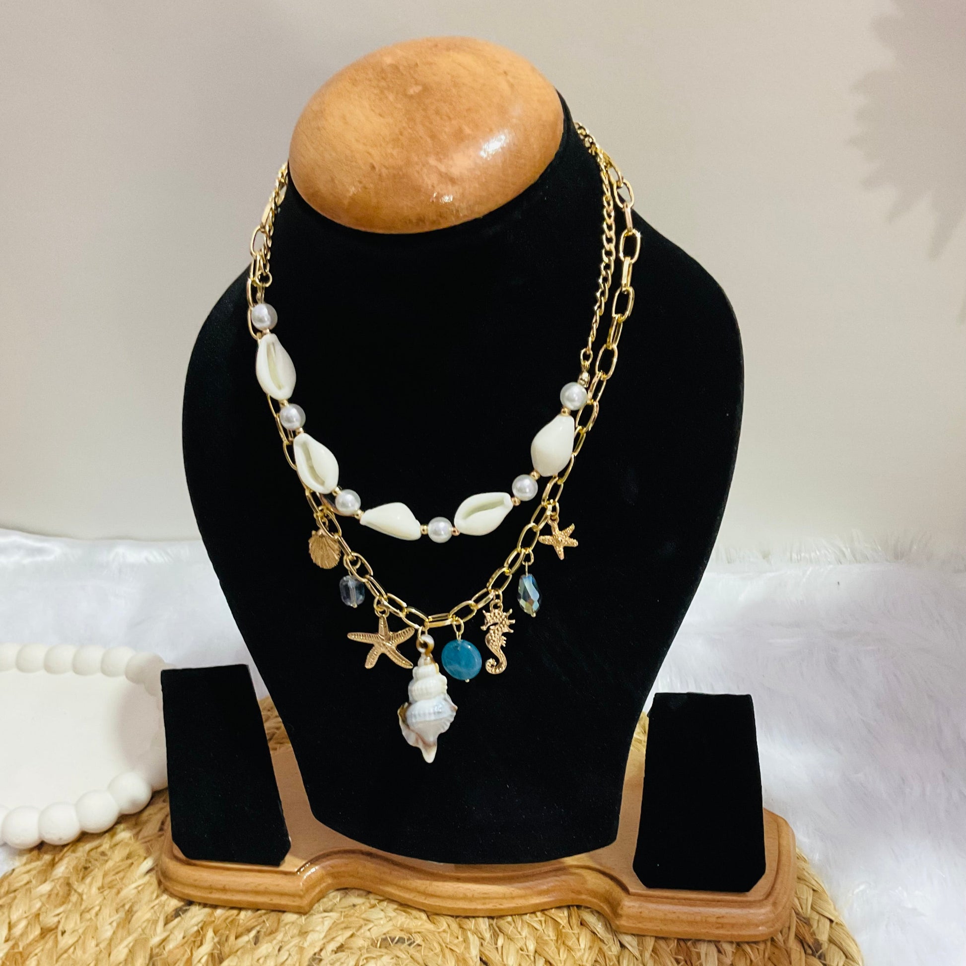 Necklace with starfish and shell charms on a black bust against a white background