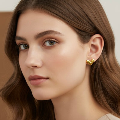 Close-up of a woman wearing a gold heart-shaped earring with a neutral background