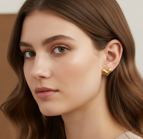Close-up of a woman wearing a gold heart-shaped earring with a neutral background